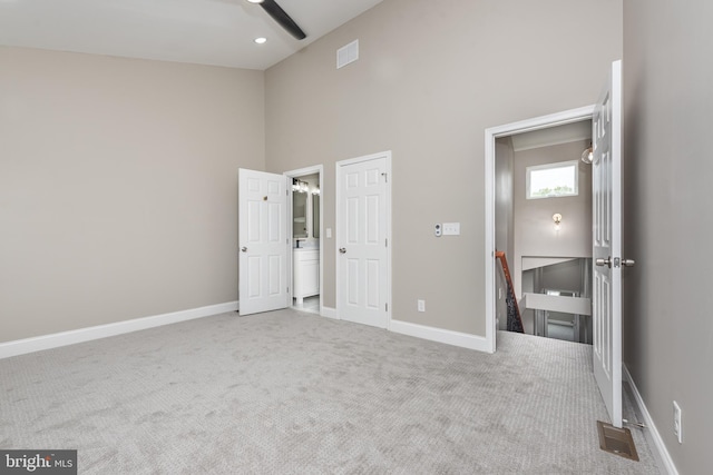 unfurnished bedroom with carpet, a towering ceiling, and ceiling fan