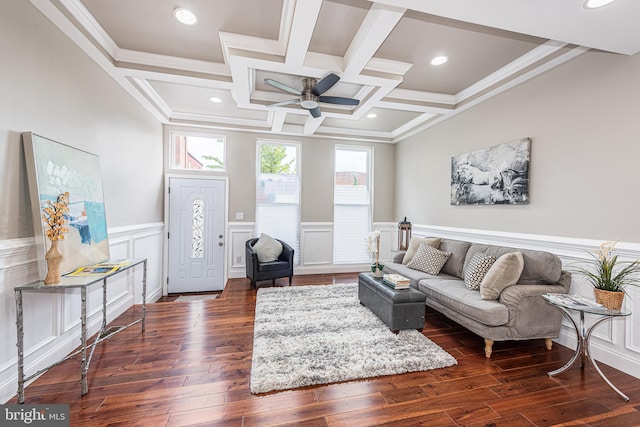 living room featuring dark wood-type flooring, coffered ceiling, ceiling fan, ornamental molding, and beam ceiling