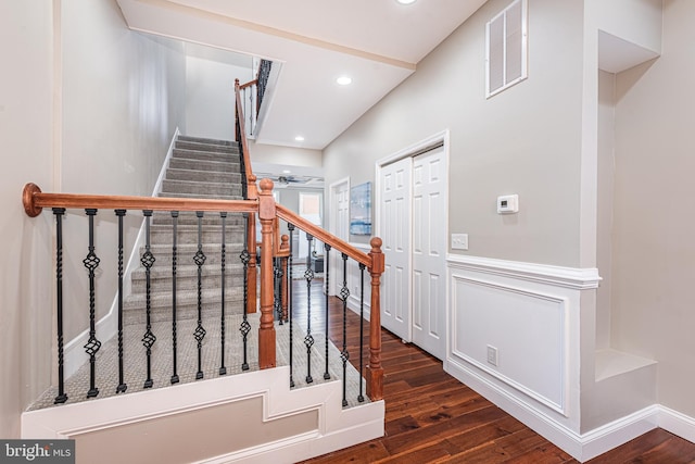 staircase with ceiling fan, hardwood / wood-style floors, and lofted ceiling