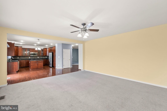 unfurnished living room featuring ceiling fan and dark wood-type flooring