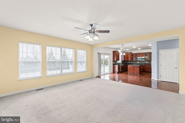 unfurnished living room with dark hardwood / wood-style flooring, ceiling fan, and a healthy amount of sunlight