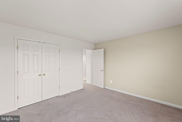 unfurnished bedroom with light colored carpet and a closet