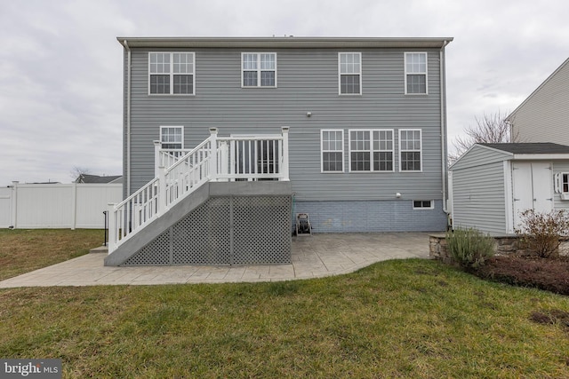 rear view of property with a deck, a patio area, and a lawn