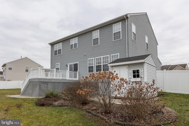 back of house featuring a deck and a lawn