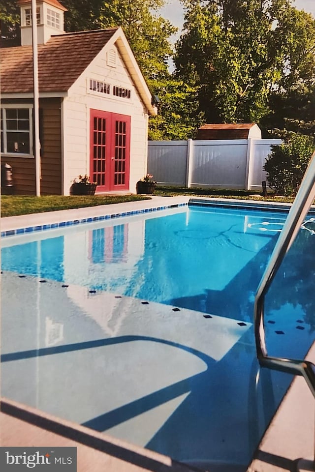 view of pool with an outbuilding and french doors