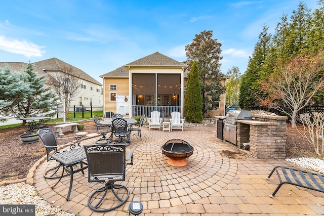 view of patio / terrace with grilling area, a sunroom, an outdoor kitchen, and an outdoor fire pit