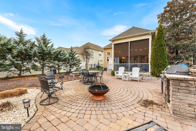 view of patio featuring a fire pit, a sunroom, and exterior kitchen