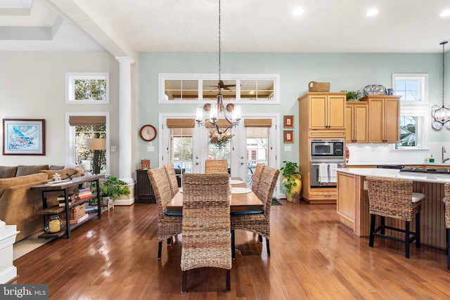 dining area featuring a notable chandelier, decorative columns, wood-type flooring, and french doors