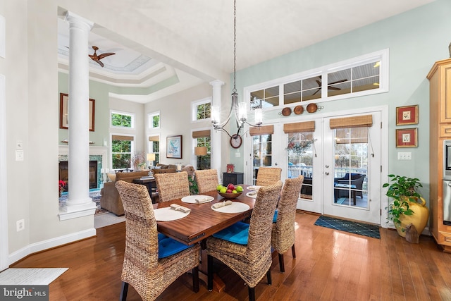 dining room with french doors, ceiling fan with notable chandelier, a raised ceiling, wood-type flooring, and a high ceiling