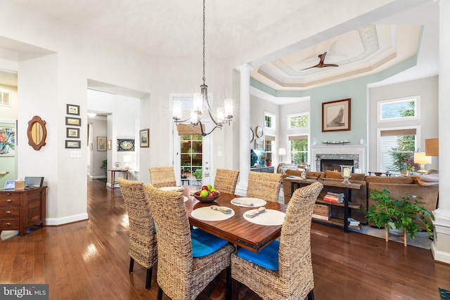 dining space featuring a tray ceiling, a towering ceiling, dark wood-type flooring, and ceiling fan with notable chandelier