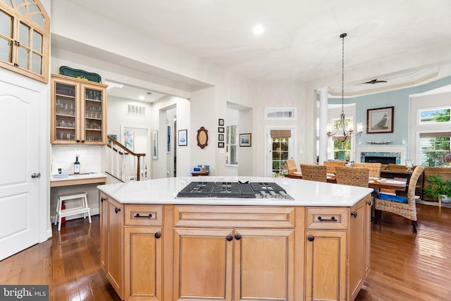 kitchen featuring pendant lighting, stainless steel gas stovetop, a center island, and dark wood-type flooring