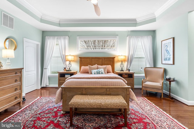 bedroom with ceiling fan, dark hardwood / wood-style floors, crown molding, and a tray ceiling