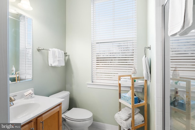 bathroom featuring vanity, toilet, walk in shower, and plenty of natural light