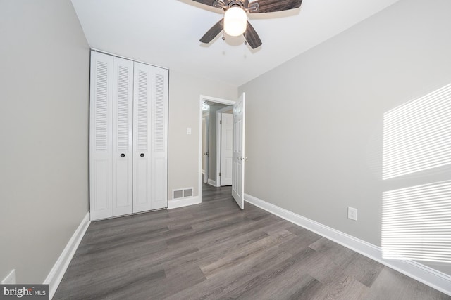 unfurnished bedroom with ceiling fan, a closet, and dark hardwood / wood-style floors