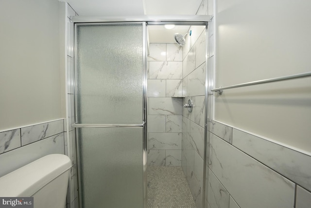 bathroom with a shower with shower door, tile walls, and toilet