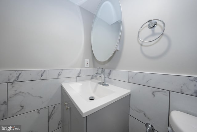 bathroom featuring vanity, toilet, and tile walls