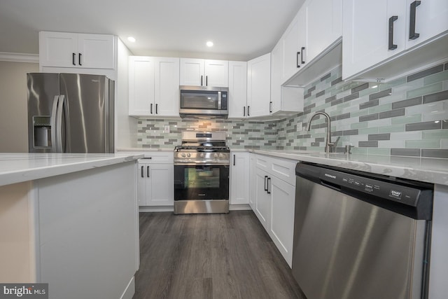 kitchen featuring light stone countertops, backsplash, stainless steel appliances, white cabinets, and dark hardwood / wood-style floors