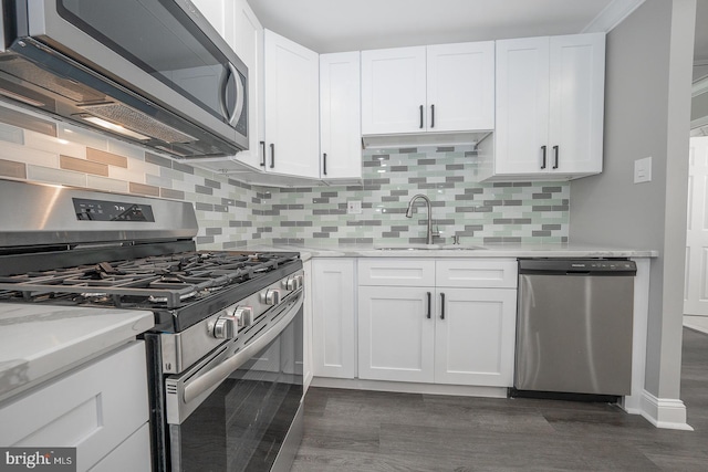 kitchen with appliances with stainless steel finishes, backsplash, light stone counters, sink, and white cabinets