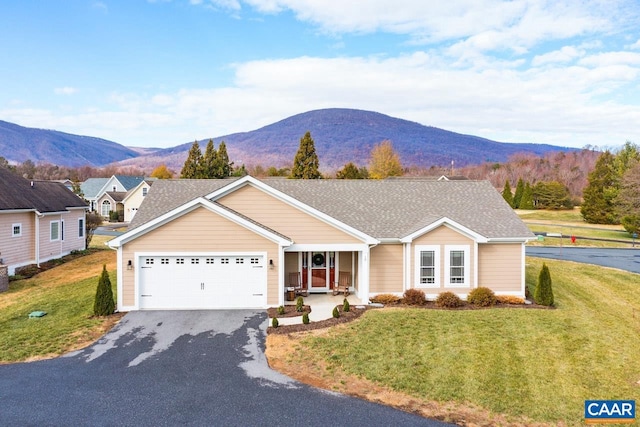 ranch-style home with covered porch, a mountain view, a garage, and a front lawn