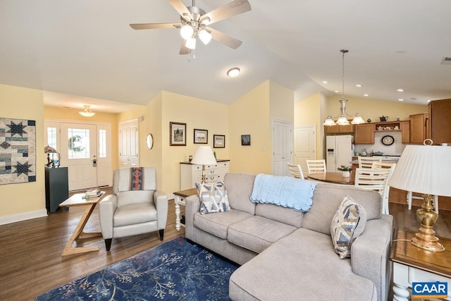 living room with ceiling fan with notable chandelier, dark hardwood / wood-style flooring, and vaulted ceiling