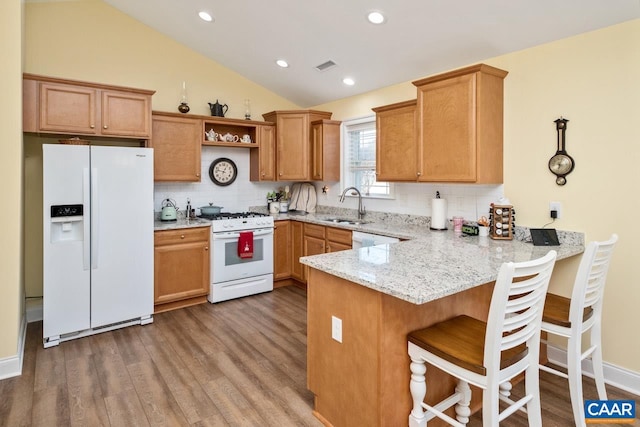 kitchen featuring kitchen peninsula, white appliances, lofted ceiling, and sink