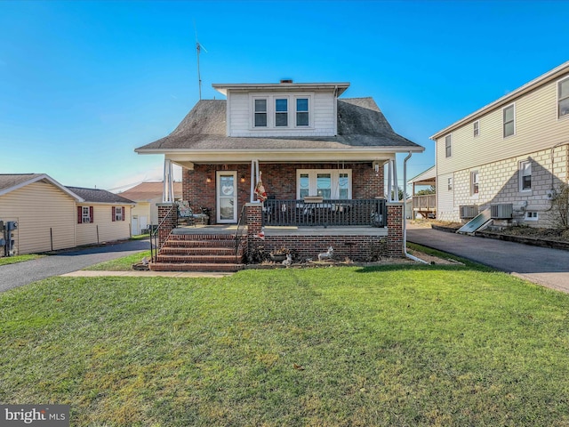 view of front of property featuring cooling unit, covered porch, and a front yard