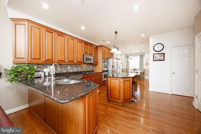 kitchen with sink, a center island, hanging light fixtures, kitchen peninsula, and appliances with stainless steel finishes