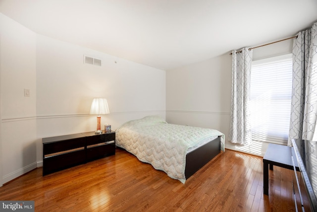 bedroom with hardwood / wood-style floors and multiple windows