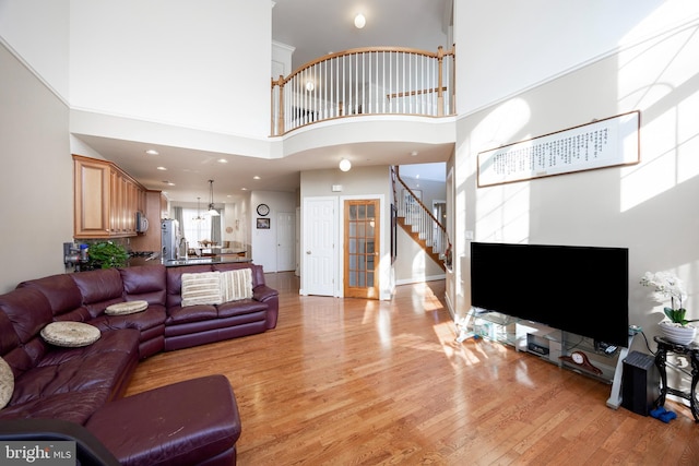 living room with sink, light hardwood / wood-style floors, and a high ceiling