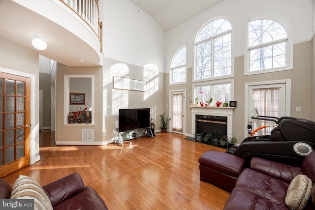 living room featuring a fireplace, a towering ceiling, and hardwood / wood-style flooring