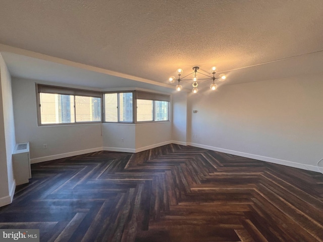 empty room featuring a textured ceiling and dark parquet floors