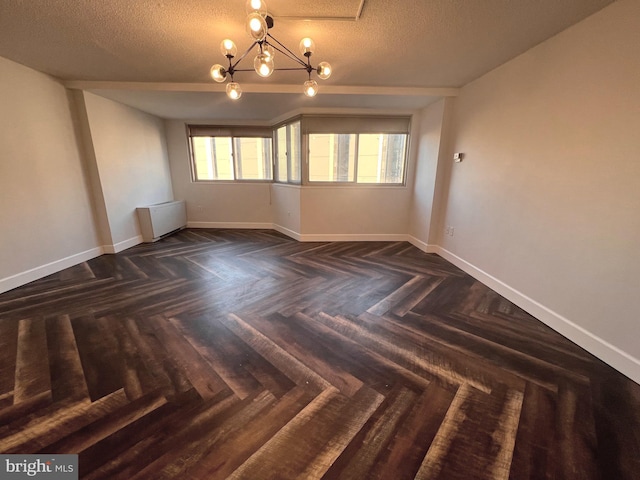 spare room featuring plenty of natural light, a textured ceiling, radiator, and a notable chandelier