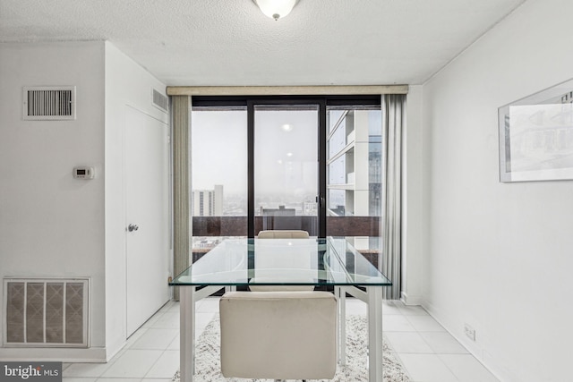 tiled dining space featuring a textured ceiling and a wall of windows