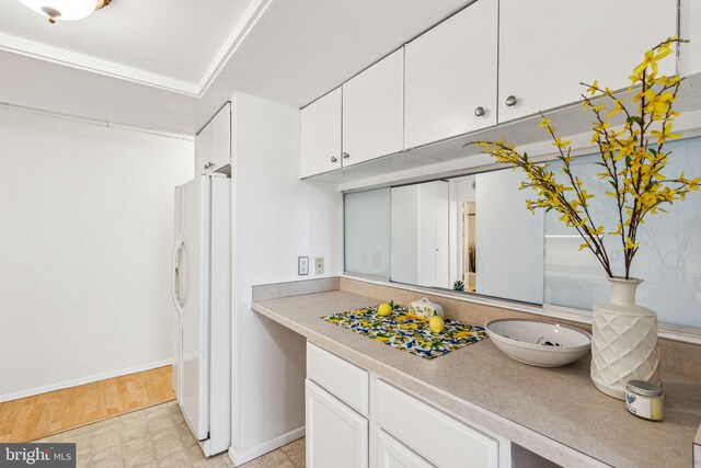 kitchen with white cabinetry, light wood-type flooring, and white fridge with ice dispenser