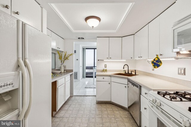 kitchen featuring white appliances, a tray ceiling, white cabinetry, and sink