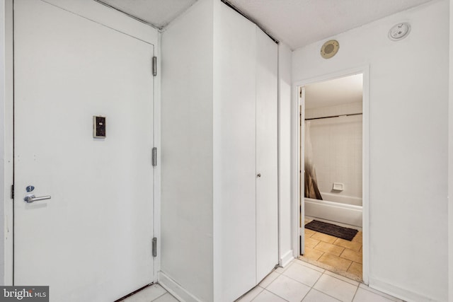 hall featuring light tile patterned flooring and a textured ceiling