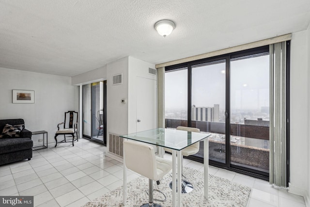 dining room featuring a textured ceiling, expansive windows, and light tile patterned flooring