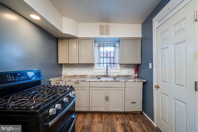 kitchen featuring tasteful backsplash, sink, black gas stove, gray cabinets, and dark hardwood / wood-style floors