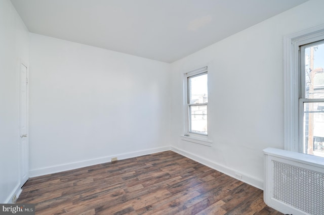 unfurnished room featuring radiator heating unit and dark hardwood / wood-style floors