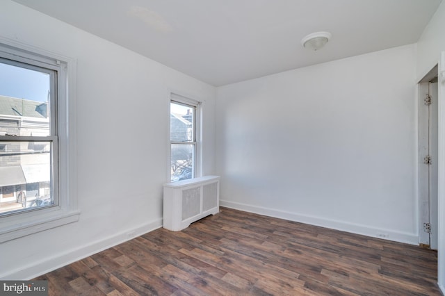 spare room with dark hardwood / wood-style flooring and radiator heating unit