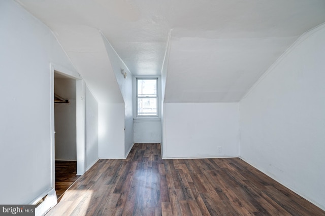 additional living space with dark hardwood / wood-style floors and vaulted ceiling