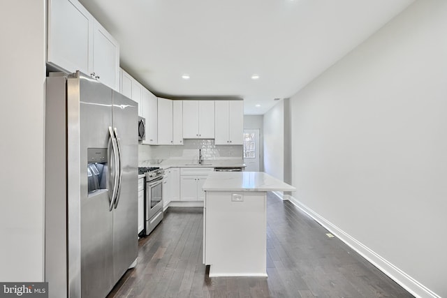 kitchen featuring appliances with stainless steel finishes, a center island, white cabinetry, and dark wood-type flooring