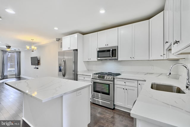 kitchen featuring pendant lighting, white cabinets, sink, a kitchen island, and stainless steel appliances