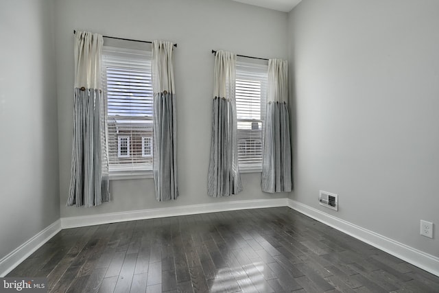 spare room featuring dark hardwood / wood-style flooring and plenty of natural light