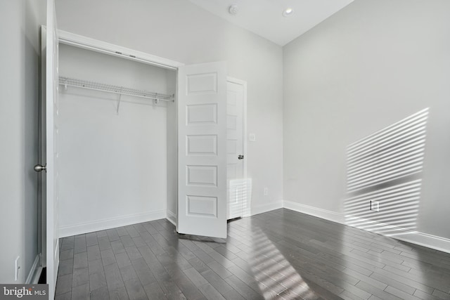 unfurnished bedroom featuring a closet and dark wood-type flooring