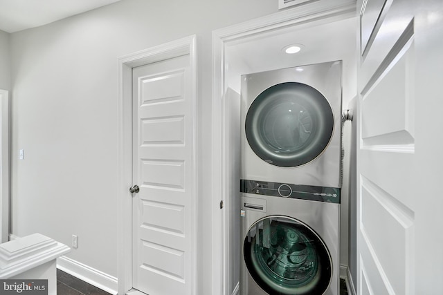 washroom with stacked washer and dryer and dark tile patterned floors