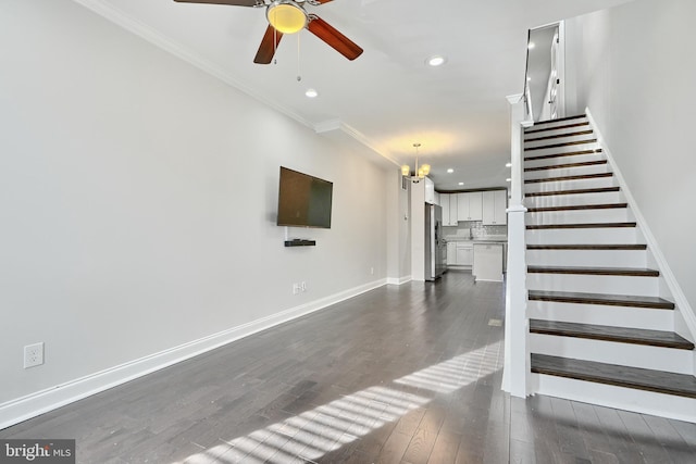 stairway with crown molding, hardwood / wood-style floors, and ceiling fan with notable chandelier