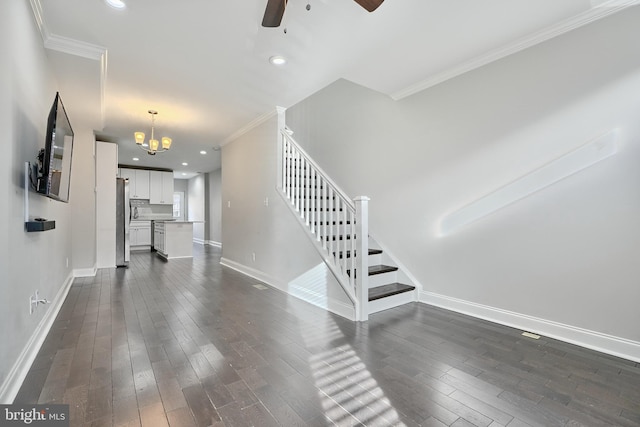 unfurnished living room with ornamental molding, ceiling fan with notable chandelier, and dark wood-type flooring