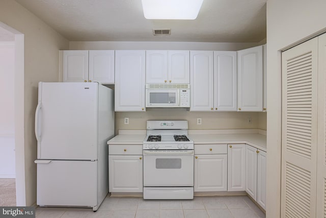 kitchen featuring white cabinetry, white appliances, light tile patterned floors, and a textured ceiling