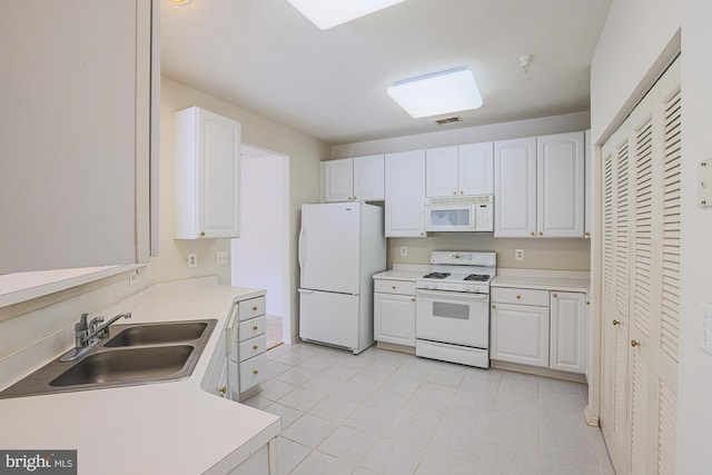 kitchen with sink, white appliances, white cabinets, and light tile patterned floors